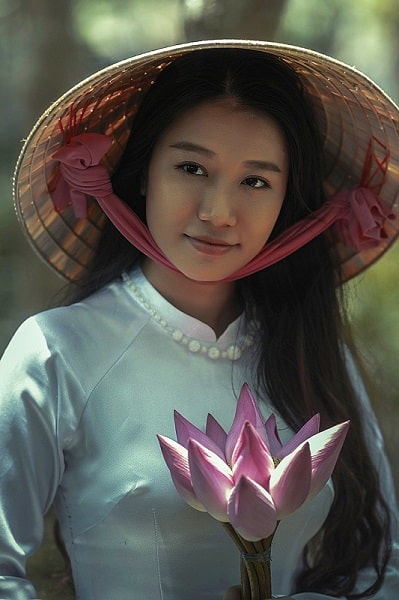una donna asiatica con in mano un fiore di loto